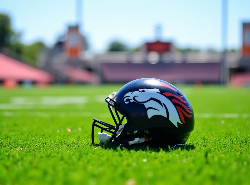 Image of a Denver Broncos helmet on a football field.